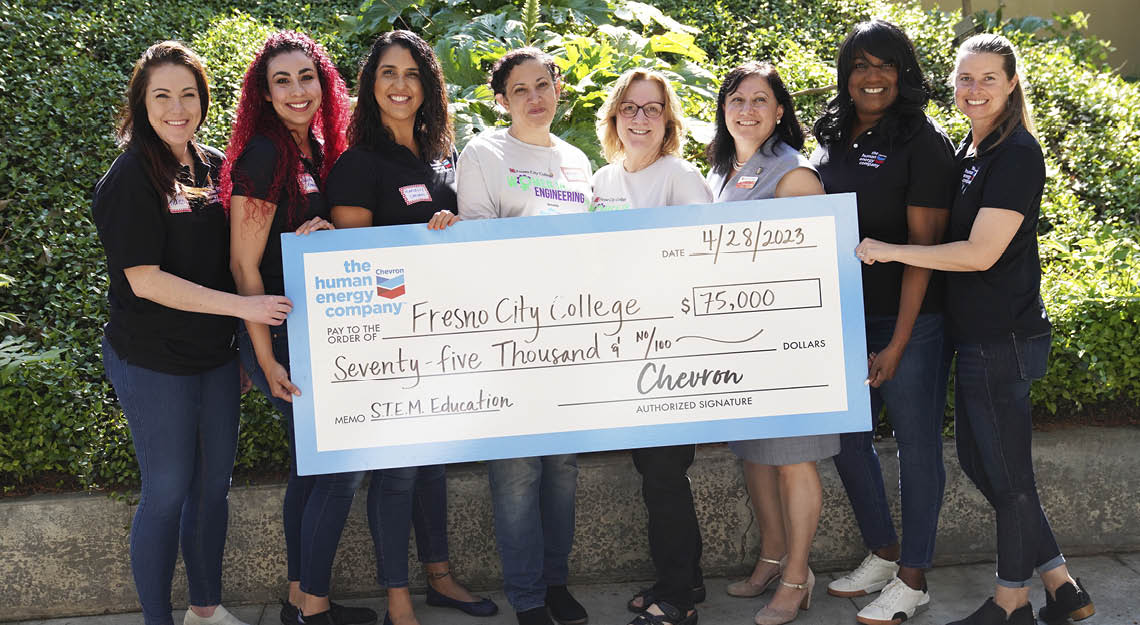 eight women hold giant check from chevron