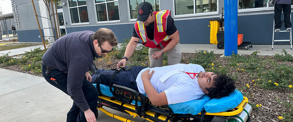 Two people working to help man being placed on stretcher.