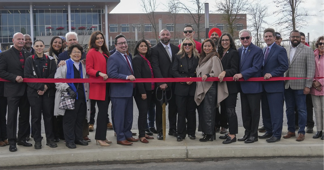 Many people standing behind a red ribbon