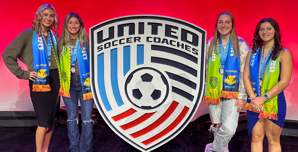 4 women standing beside emblem of United Soccer Coaches