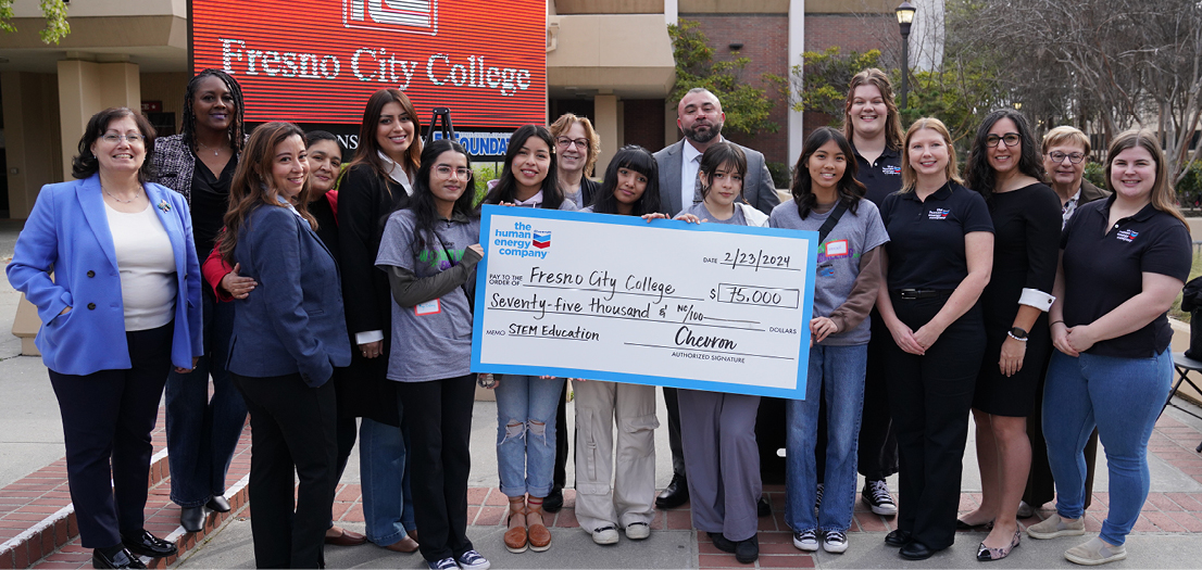 People standing around holding check from chevron