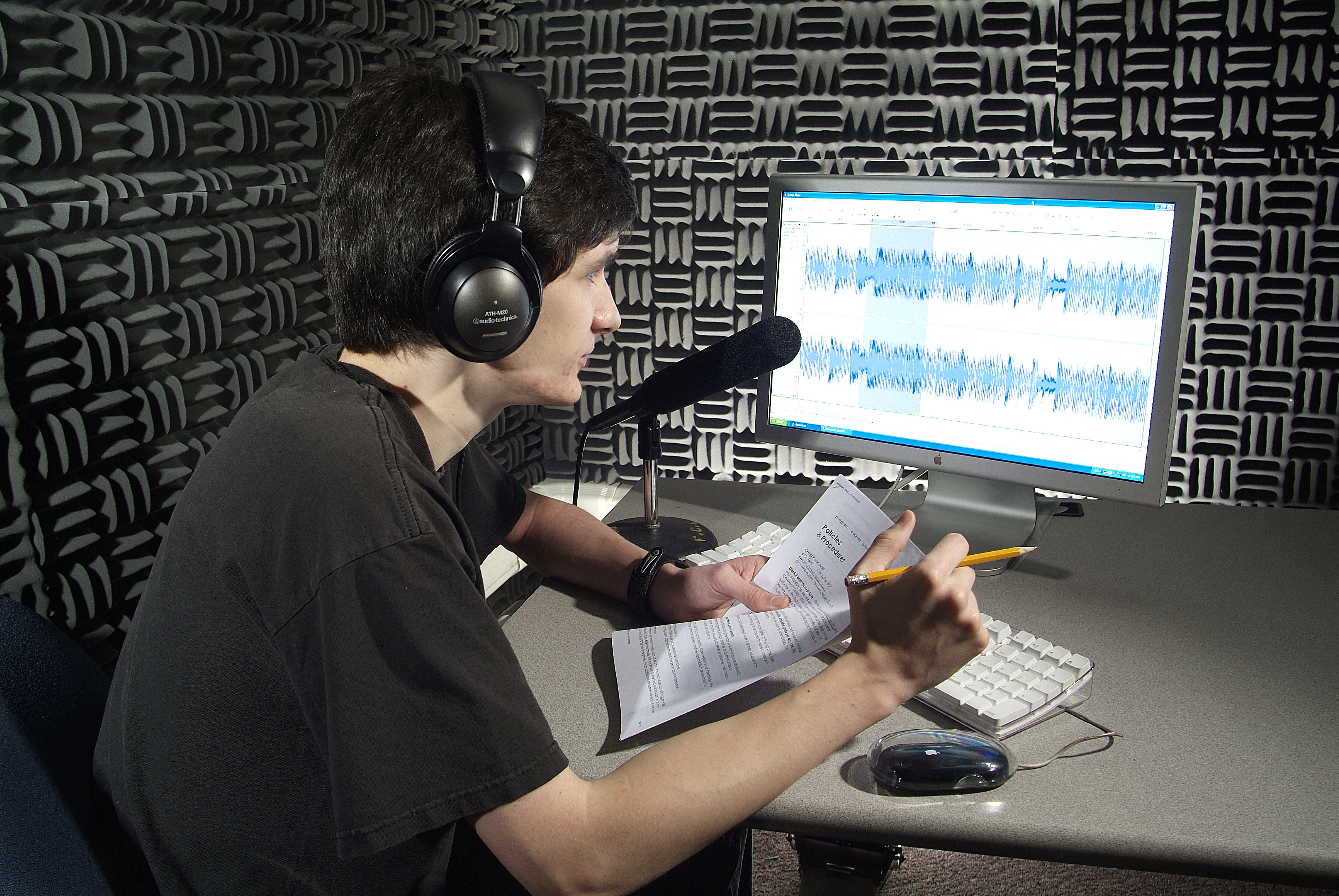      student recording and editing audio in the sound room 