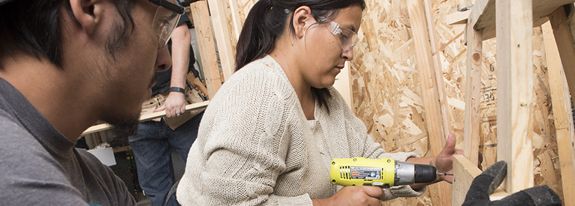 woman drilling while framing house