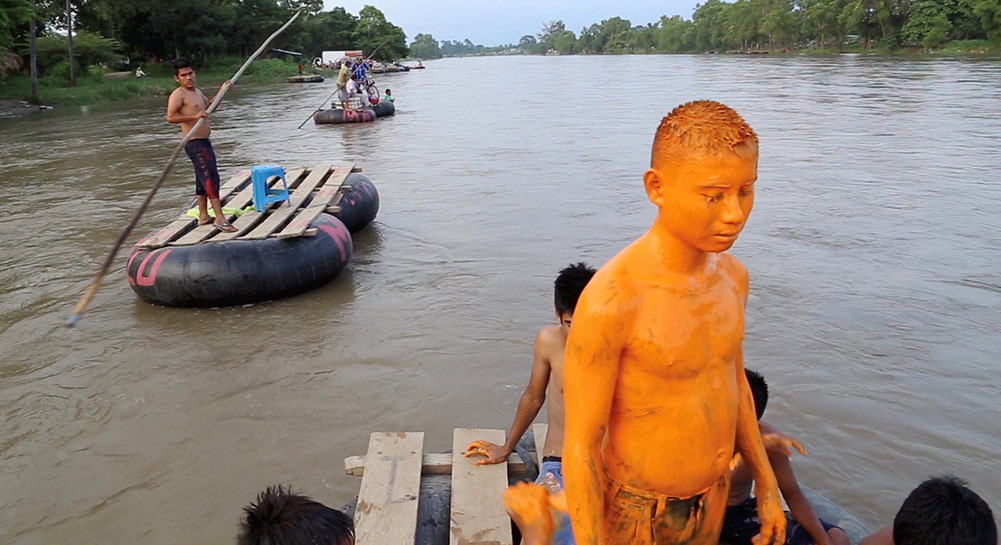 boy covered in orange mud on raft