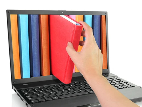 someone reaching for a book that is coming out of a laptop screen