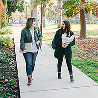 Two girls walking on sidewalk